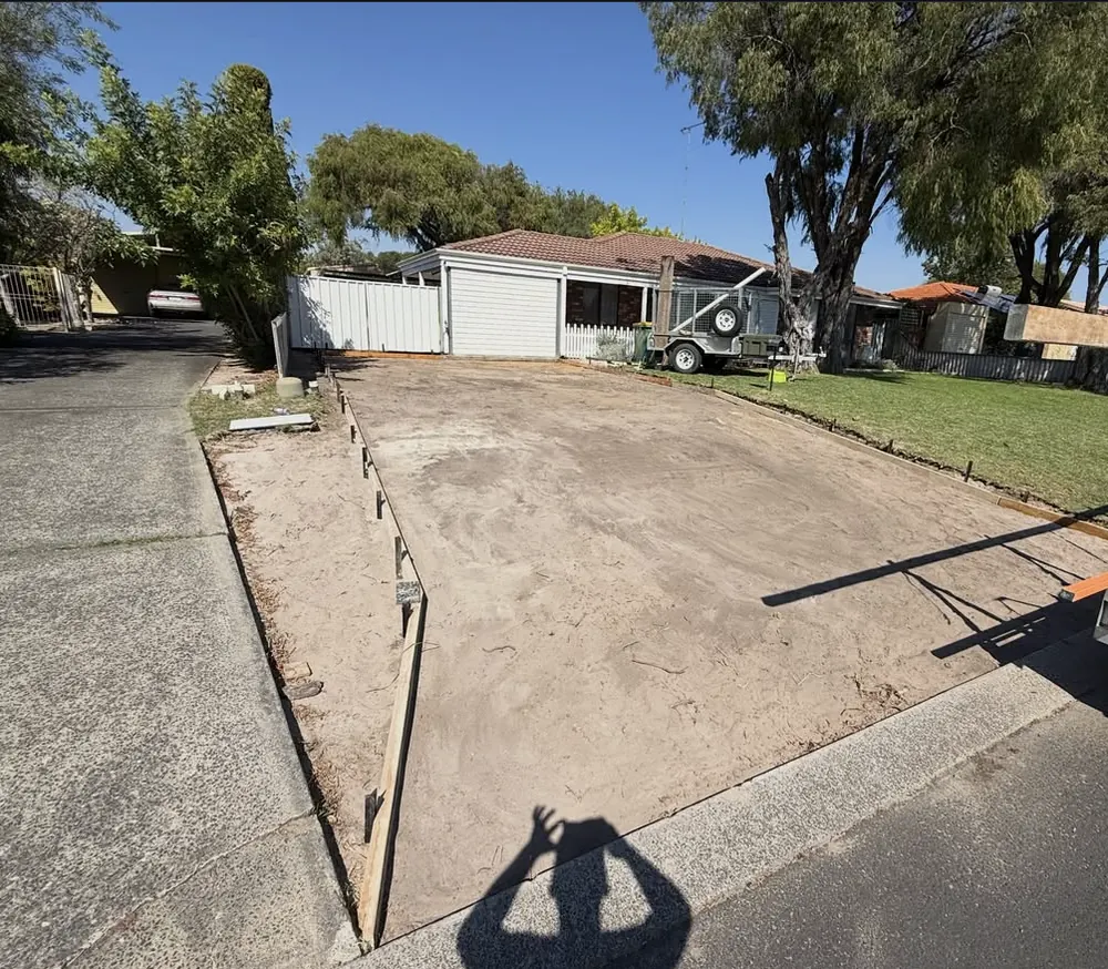 The same driveway area before the pour, bare ground with timber formwork