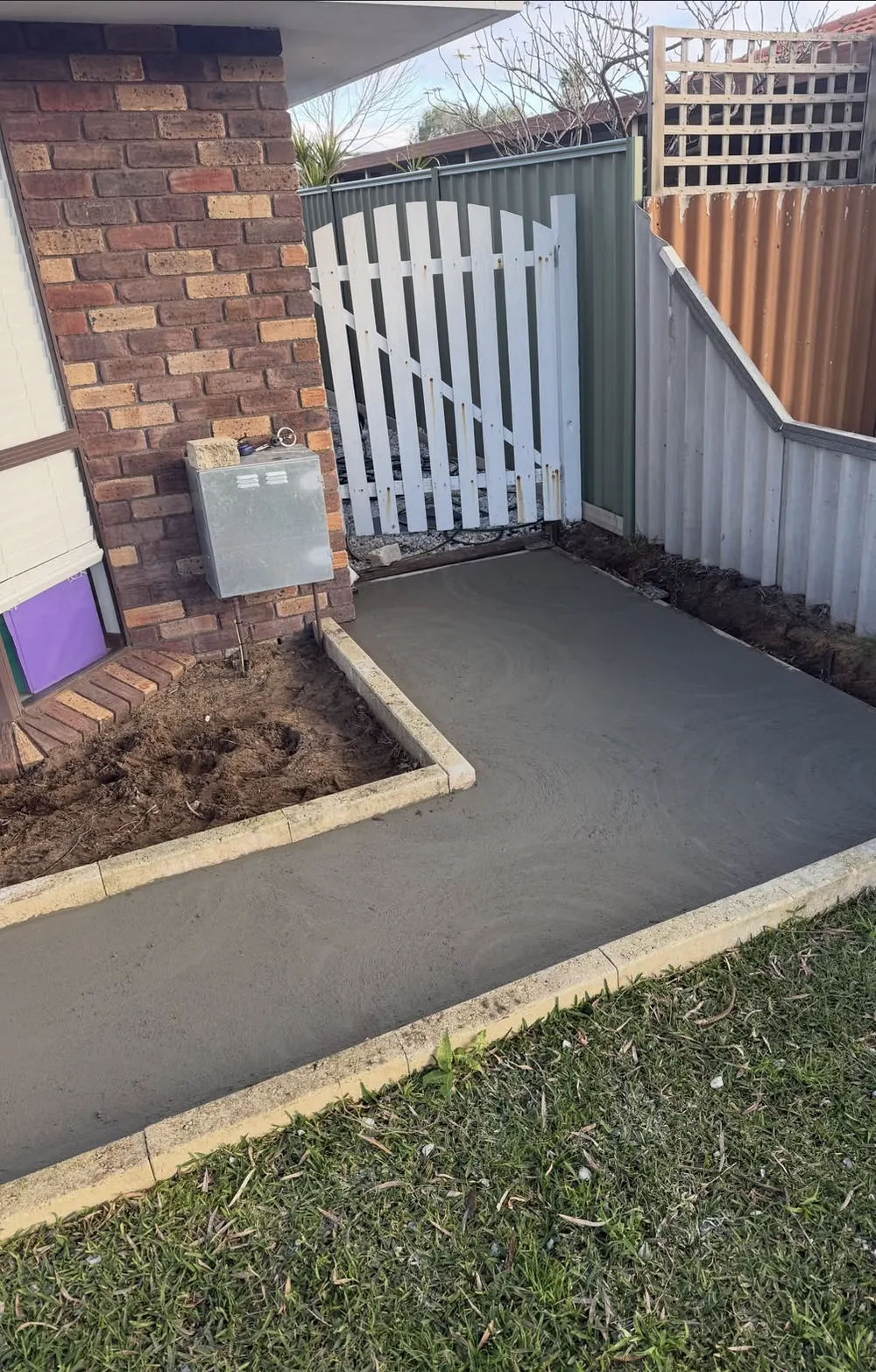 Sponge-finished concrete path curving past a white garden gate